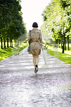 Woman at coat with umbrella walk in park