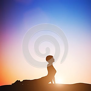 Woman in cobra yoga pose meditating at sunset. Zen