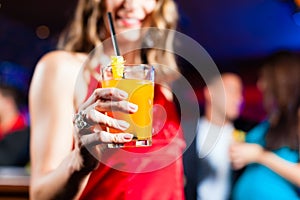 Woman with cocktail in bar or club