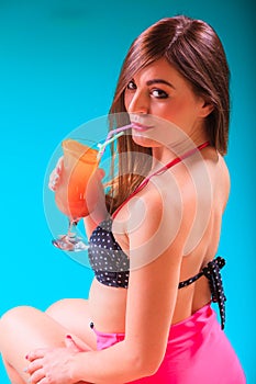 Woman with cocktail drink at swimming pool edge.