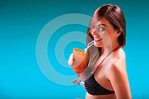 Woman with cocktail drink at swimming pool edge.