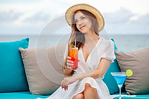 Woman with cocktail relaxing in outdoors bar at tropical sea resort