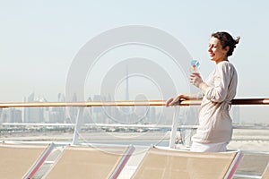 Woman with cocktail standing on cruise liner deck