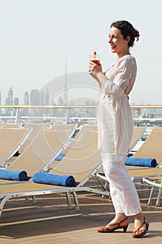 Woman with cocktail standing on cruise liner deck