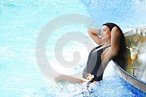 Woman with cocktail in swimming pool