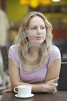 Woman With Coffee Cup Leaning On Table In Mall