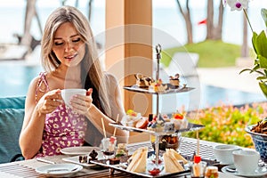 Woman with coffee cup and sweet cake set in outdoors resort restaurant