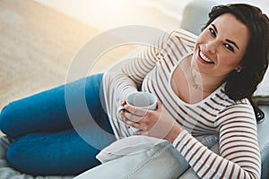 Woman, coffee and happy for portrait on sofa to relax on break, home and espresso in living room. Person, tea cup and