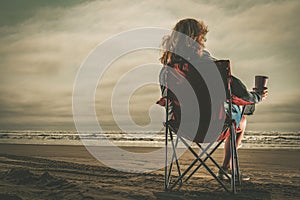 Woman with Coffee in Her Hand Enjoying Free Time on a Beach photo