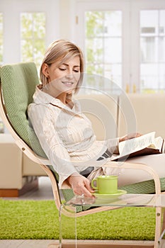 Woman with coffee mug and book at home