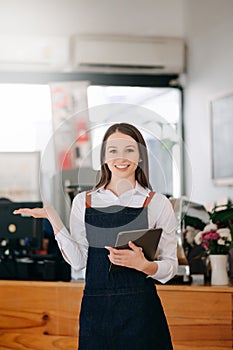 Woman coffee shop owner holding  notepad and digital tablet ready to receive orders.  in cafe restaurant. woman barista cafe