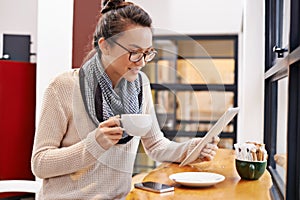 Woman, coffee shop and tablet with freelancer job and social media in cafe with cappuccino. Website, hot drink and