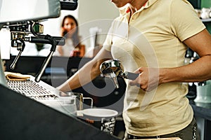 Woman coffee shop worker preparing coffee on professional coffee machine