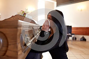 Woman with coffin crying at funeral in church