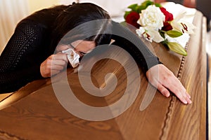 Woman with coffin crying at funeral in church