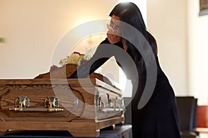 Woman with coffin crying at funeral in church