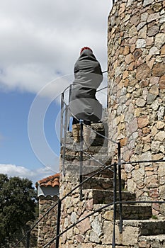 Woman with cold covered with a blanket climbing a ladder of a tower in winter, rear view photo