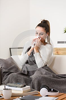 Woman in cold and flu sneezing nose with tissue