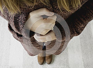 A woman is cold and wrapping herself in her cozy, warm winter sweater to warms herself