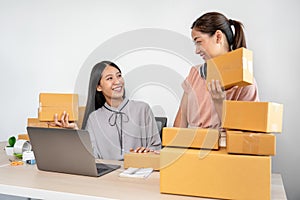 Woman colleague is preparing packing products in parcel boxes for delivery to client after checking customer
