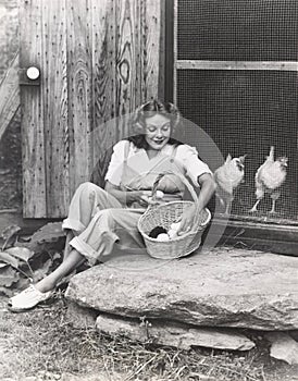 Woman collecting eggs from chickens