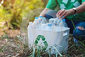 A woman collecting garbage plastic bottles into a recycle bin