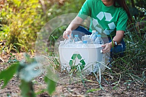 A woman collecting garbage plastic bottles into a recycle bin