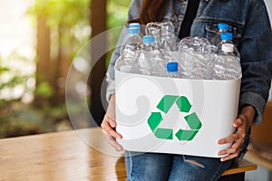 A woman collecting and holding a recyclable garbage plastic bottles into a trash bin