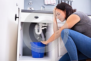 Woman Collecting Leaking Water In Bucket