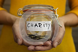 Woman collecting money for charity and holds jar with coins.