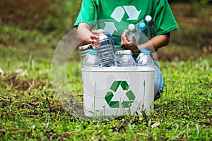 A woman collecting and putting plastic bottles into a recycle bin