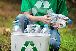 A woman collecting and putting plastic bottles into a recycle bin