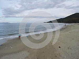 A woman collecting shels on almost empty beach.