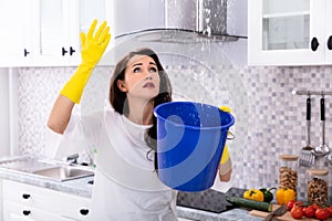 Woman Collecting Water Leaking From Ceiling In Bucket