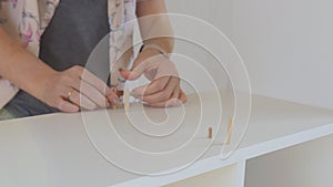 A woman collects a bookcase in the room. Woman assembling a shelf.