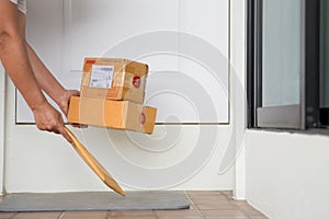 Woman collects parcel at door. box near door on floor. Online shopping, boxes delivered to your front door. Easy to steal when