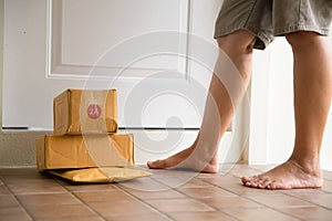 Woman collects parcel at door. box near door on floor. Online shopping, boxes delivered to your front door. Easy to steal when