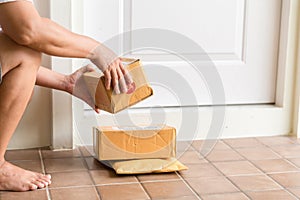 Woman collects parcel at door. box near door on floor. Online shopping, boxes delivered to your front door. Easy to steal when