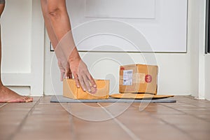 Woman collects parcel at door. box near door on floor. Online shopping, boxes delivered to your front door. Easy to steal when