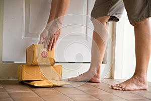 Woman collects parcel at door. box near door on floor. Online shopping, boxes delivered to your front door. Easy to steal when