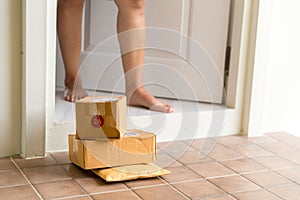 Woman collects parcel at door. box near door on floor. Online shopping, boxes delivered to your front door. Easy to steal when
