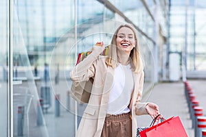 Woman with colored bags with goods near a modern shopping mall