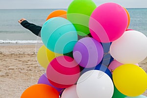 Woman with colorful balloons on the beach