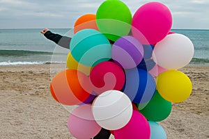 Woman with colorful balloons on the beach