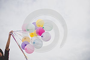 Woman with colorful balloons outside blue sky.