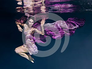 Woman in colorful clothes swimming underwater