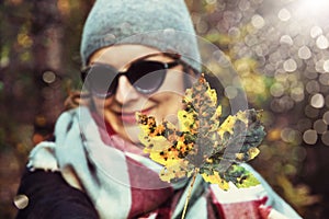 Woman with colorful maple leaf in autumn nature, sun overlays