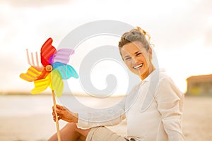 Woman with colorful windmill toy sitting on beach