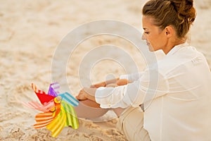 Woman with colorful windmill toy sitting on beach