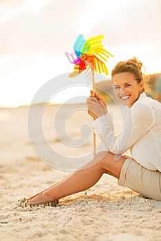 Woman with colorful windmill toy sitting on beach
